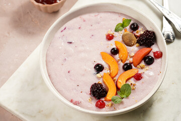 Traditional breakfast semolina porridge - purple creamy pudding with apricot slices, frozen berries, fresh mint, jelly on marble board