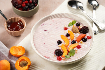 Traditional breakfast semolina porridge - purple creamy pudding with apricot slices, frozen berries, fresh mint, jelly on marble board