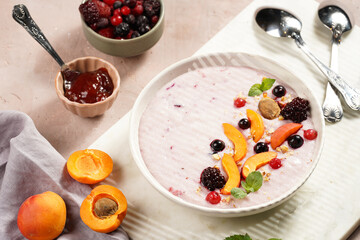 Traditional breakfast semolina porridge - purple creamy pudding with apricot slices, frozen berries, fresh mint, jelly on marble board