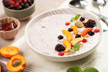 Traditional breakfast semolina porridge - purple creamy pudding with apricot slices, frozen berries, fresh mint, jelly on marble board