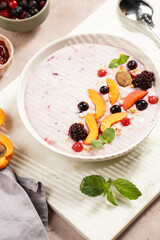 Traditional breakfast semolina porridge - purple creamy pudding with apricot slices, frozen berries, fresh mint, jelly on marble board