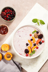Traditional breakfast semolina porridge - purple creamy pudding with apricot slices, frozen berries, fresh mint, jelly on marble board