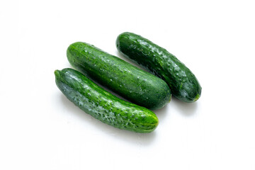 three fresh cucumbers on a white background