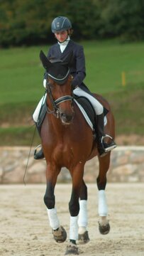 SUPER SLOW MOTION: Beautiful gelding doing travers during dressage competition. English female rider riding traver in dressage. Cinematic shot of muscular chestnut stallion performing haunches-in.
