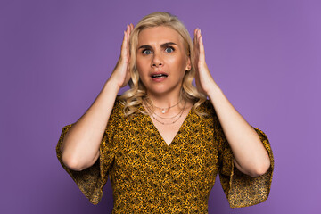 shocked blonde woman stressing because of menopause isolated on purple.
