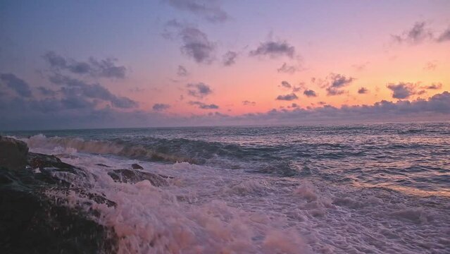 sunrise on the beach. beautiful summer scenery. rocks on the sand. calm waves on the water. clouds on the sky. wide panoramic view.