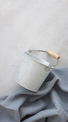 empty mini bucket on gray background with blue kitchen towel