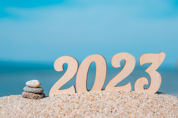 new year numbers 2023 on the beach by the sea with a cairn. the concept of tourism, recreation and...