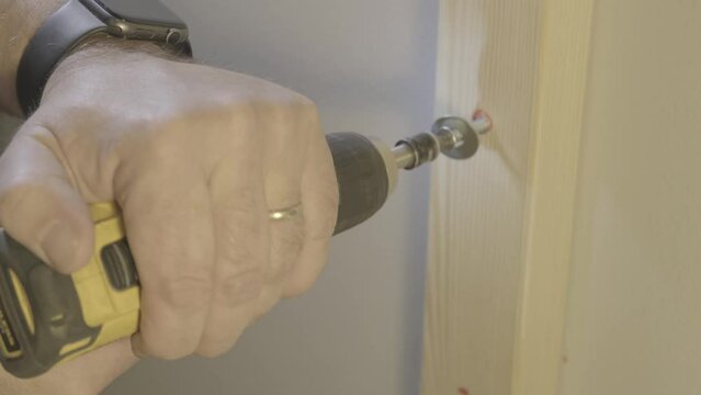 Battery powered drill used to screw wood frame to wall