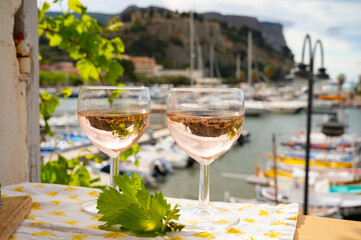 Rose wine in glasses served on outdoor terrace with view on old fisherman's harbour with colourful boats in Cassis, Provence, France