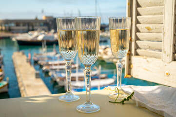Three glasses of French champagne sparkling wine and view on colorful fisherman's boats in old harbour in Cassis, Provence, France