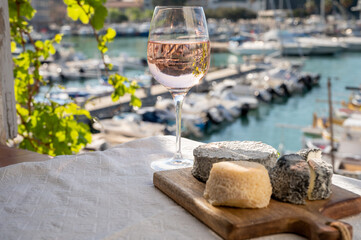 French goat cheeses crottin and selles-sur-cher served with view on boats in harbor of Cassis, Provence, France with glass of dry rose Provencal wine