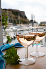 Rose wine in glasses served on outdoor terrace with view on old fisherman's harbour with colourful boats in Cassis, Provence, France