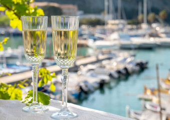 Two glasses of French champagne sparkling wine and view on colorful fisherman's boats in old harbour in Cassis, Provence, France