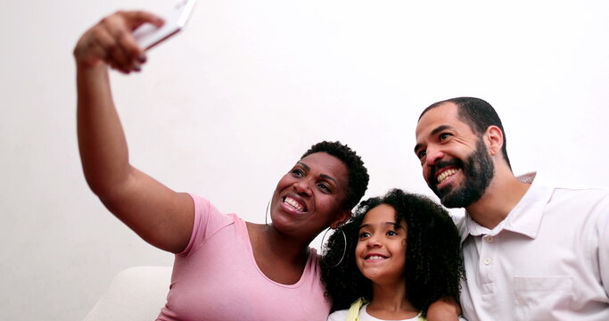 Happy multiracial family taking selfie with smartphone device. Interracial parents take photo