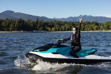 Adventurous Caucasian Woman on Water Scooter riding in the Ocean. Modern City in background. Downtown Vancouver, British Columbia, Canada.