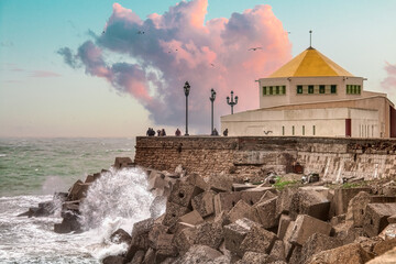 People contemplating the waves breaking against the rocks from a bastion on the La Caleta...