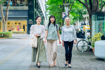 街を歩くさまざまな世代の女性3人
