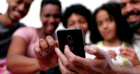 Happy mixed race family looking at phone device laughing and smiling