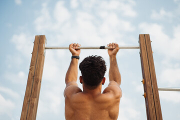 Fit sportsman doing pull ups on bar