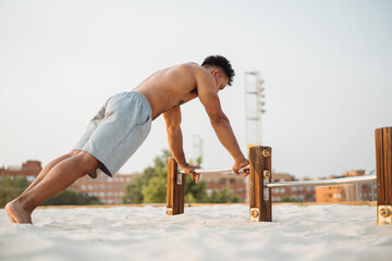 Hispanic ethnic sportsman doing parallel bar push ups