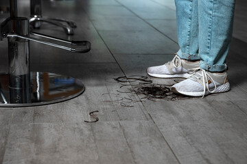 Cut hair lies on the floor in the hairdressing salon at the feet of the master hairdresser