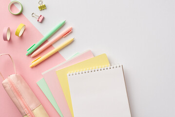 Back to school concept. Top view photo of colorful school supplies notebooks pens adhesive tape binder clips and pencil-case on bicolor white and pink background with empty space