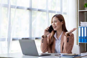 Beautiful Asian woman executives, business executives, marketing executives are talking on the phone with customers to contact the company for marketing. Marketing management concept.