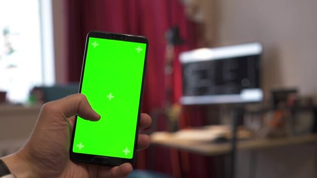 Man holding smartphone with green screen