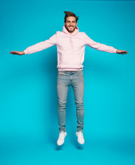 Full size photo of young happy excited smiling positive man jumping isolated on light blue color background.