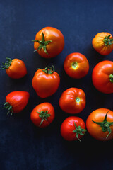Fresh organic tomatoes, picked from the garden, on dark background. Flat lay.