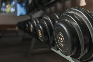 Fototapeta na wymiar Black dumbbells on metal racks in the gym.