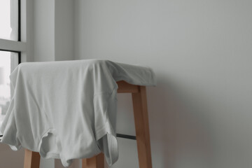 Fototapeta na wymiar White t-shirt hanging on the chair with white background.