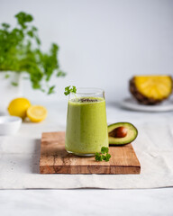 Green smoothie with pineapple, avocado, banana, parsley, lemon juice in a glass, sprinkled with chia seeds. Healthy dieting and nutrition, vegan und vegetarian concept.