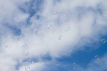 Soap bubbles fly across the blue sky with clouds