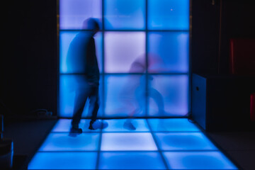 Children dance at the disco on glowing panels, blurry background. Blurry movement of people dancing