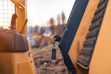 Close-up of keys and control knobs in open cab of heavy equipment. Blurred background fire in the...