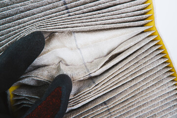 Auto mechanic hand open the old air filter that is clogged in the car for inspection