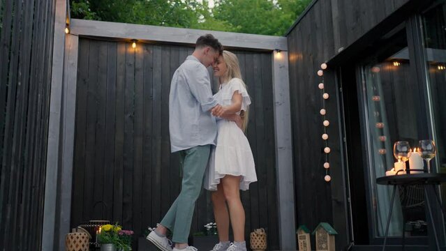 Young couple in love dancing outdoors, weekend away in tiny house in countryside, travel and holiday concept.
