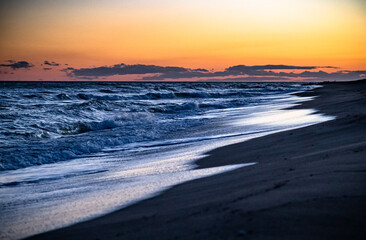 Last lights of the sunset over the waves on beach
