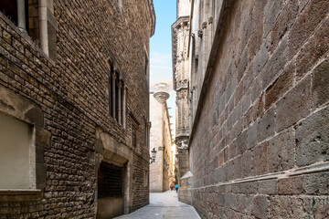 Tall, stone and brick walls surround a narrow alley near the Cathedral in the Gothic Quarter of Barcelona, Spain. © Kirk Fisher