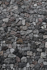 vertical view of wall with masonry of various stones. Background and texture of stone wall surface