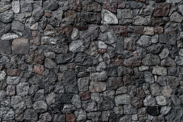 horizontal view of wall with masonry of various stones. Background and texture of stone wall surface