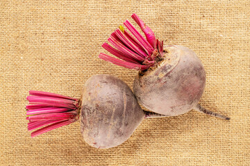Two sweet red beetroots on jute fabric, close-up, top view.