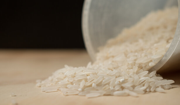Some white raice grains spiled on a wooden table 