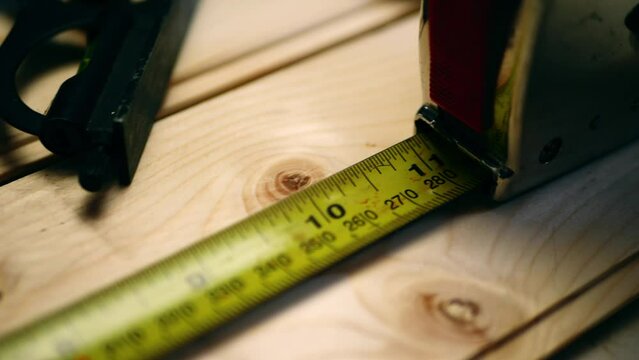 Carpenter measuring wood with a tape measure