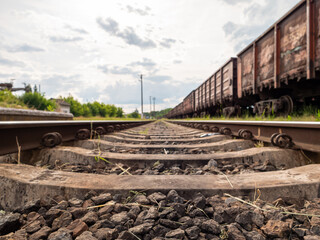 Old railway rails and sleepers close-up. Grading yard, freight wagons in the background....