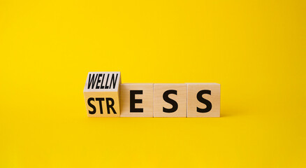 Wellness and Stress symbol. Turned Wooden cubes with word Wellness and Stress. Beautiful yellow background. Business and Wellness and Stress concept. Copy space.