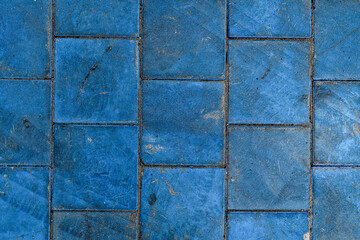 Close-up top view on texture of paving slabs covered with blue paint. Pavement tile pattern.