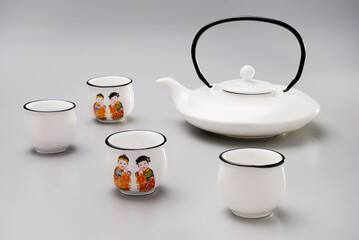 Tea kit with ceramic tea kettle and four cups, with oriental illustration, isolated on white